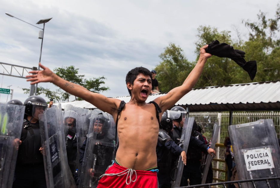 Viernes 19 de octubre. Un miembro de la caravana grita pidiendo calma a sus compatriotas, para evitar que reinara el caos en el puente que cruza el río Suchiate. Según información oficial mexicana, dos policías resultaron lesionados después de la escaramuza. Algunos migrantes, desesperados por el amontonamiento sobre el puente, lanzaron piedras para intentar espantar a los federales (Fuente: Fred Ramos, El Faro).