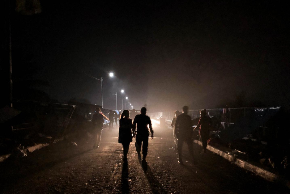 Sábado 20 de octubre. Una pareja de migrantes hondureños camina sobre el puente fronterizo entre Guatemala y México, durante la noche. Con el paso del tiempo, un puente donde apenas cabían los cuerpos fue teniendo espacios libres, gracias a la decisión de cientos de pasar de forma irregular (Fuente: Fred Ramos, El Faro).