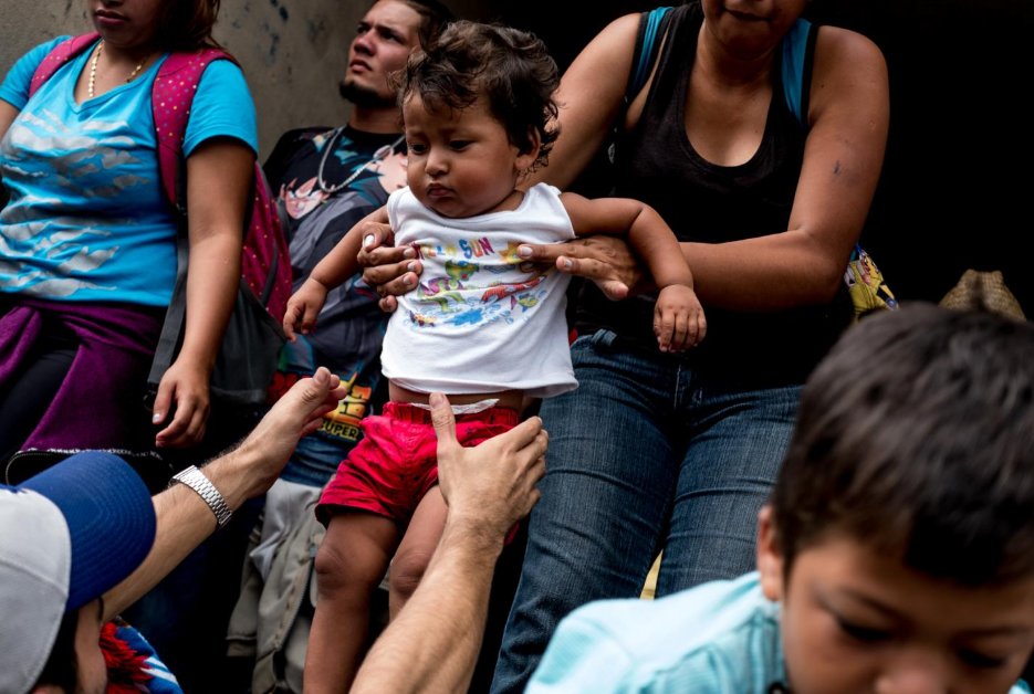 Migrantes centroamericanos ayudan a bajar a una niña de un camión que les dio aventón, en Isla, Veracruz, el 3 de noviembre. Cientos de niños viajaron en camiones desde Sayula de Alemán, Veracruz, a Puebla: un trayecto de 350 kilómetros.