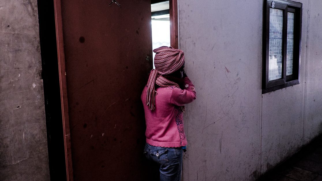 Una niña observa a sus vecinos limpiando, de forma colectiva, el aseo del pasillo. Foto: Jorge Vargas | Migrar Photo