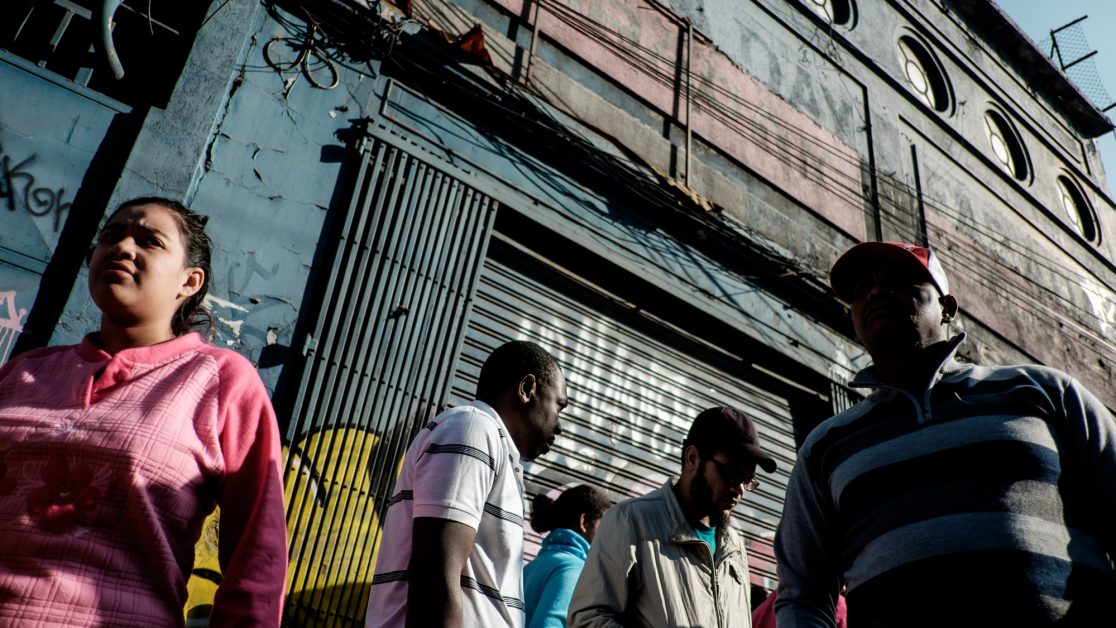 Los vecinos se organizan fuera del galpón luego de que uno de los habitantes se enfrentara duramente con el arrendador ante los constantes reclamos por las precarias condiciones en las que viven. Foto: Jorge Vargas | Migrar Photo